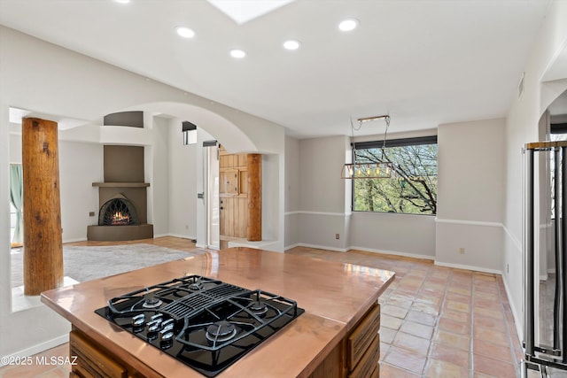 kitchen featuring light tile patterned floors, black gas cooktop, and a fireplace