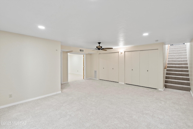 basement featuring light carpet and ceiling fan