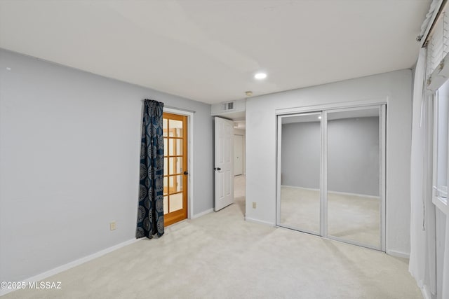 unfurnished bedroom featuring light carpet and a closet