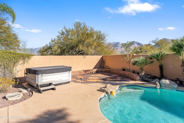 view of swimming pool featuring a hot tub, a mountain view, and a patio