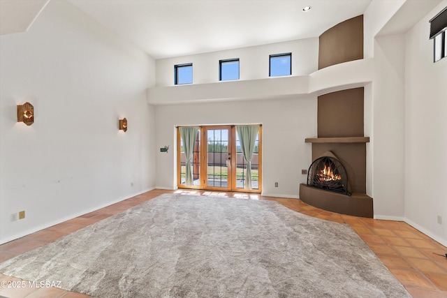 living room with a large fireplace, a towering ceiling, and light tile patterned flooring