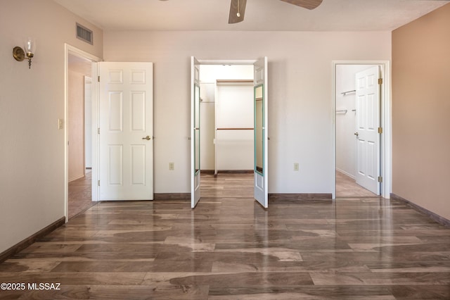 unfurnished bedroom with ceiling fan, dark hardwood / wood-style flooring, a walk in closet, and a closet