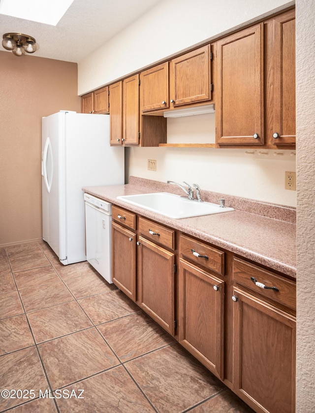 kitchen featuring white appliances, sink, and a skylight