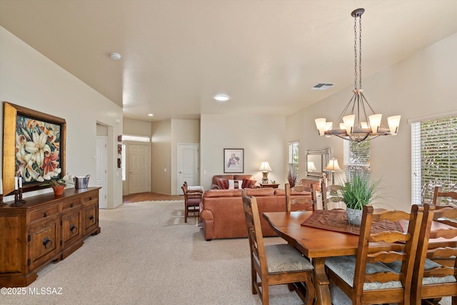 dining area with light carpet and a chandelier