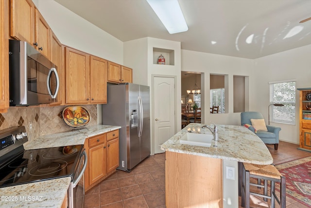 kitchen with a kitchen island with sink, a kitchen breakfast bar, sink, decorative backsplash, and appliances with stainless steel finishes