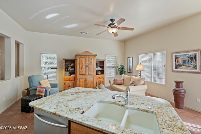 kitchen featuring ceiling fan, sink, light tile patterned floors, and light stone countertops