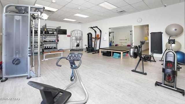 gym with a paneled ceiling and hardwood / wood-style flooring