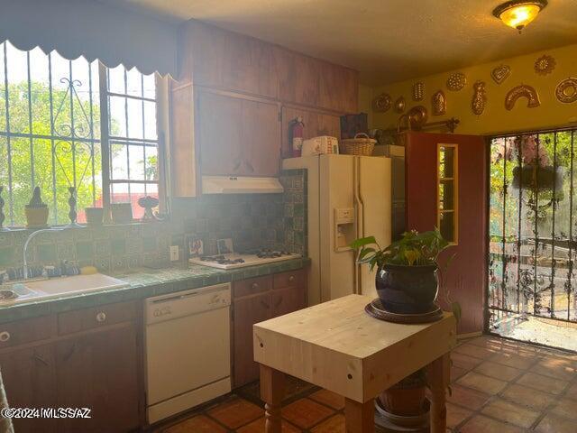 kitchen with tile countertops, decorative backsplash, sink, and white appliances