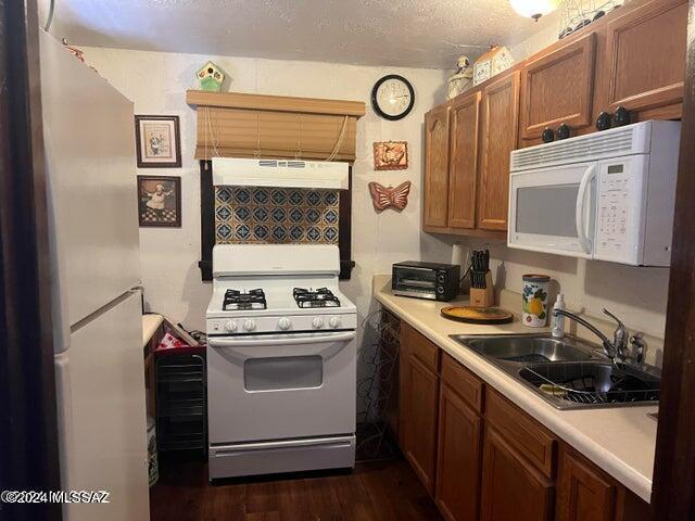 kitchen featuring custom exhaust hood, a textured ceiling, white appliances, sink, and dark hardwood / wood-style floors