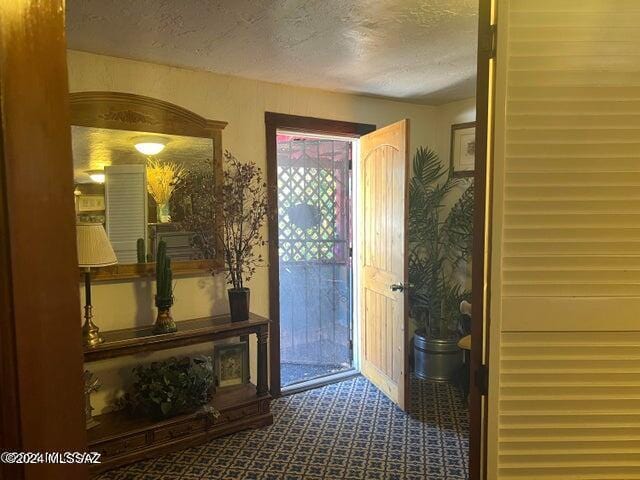 doorway to outside featuring carpet flooring and a textured ceiling