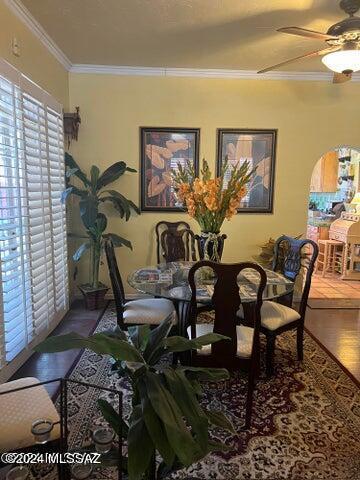 dining area featuring wood-type flooring, ceiling fan, and ornamental molding