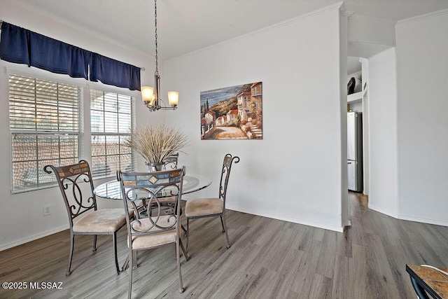 dining space with hardwood / wood-style floors, an inviting chandelier, and crown molding