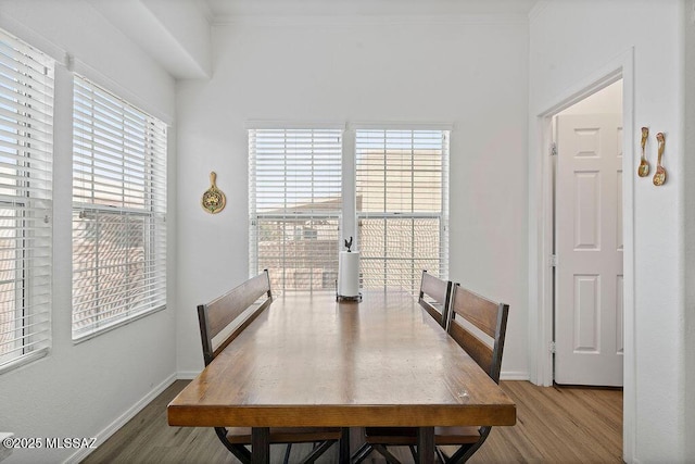 dining area with ornamental molding and light hardwood / wood-style flooring