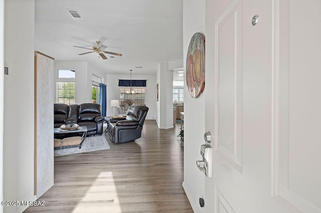 living room featuring ceiling fan with notable chandelier and light hardwood / wood-style floors