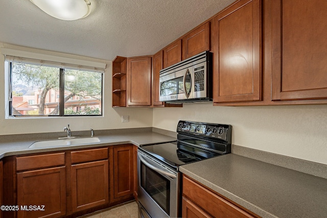 kitchen with light tile patterned flooring, a textured ceiling, stainless steel appliances, and sink