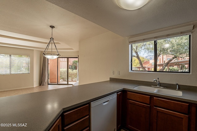 kitchen featuring kitchen peninsula, dishwashing machine, sink, and hanging light fixtures