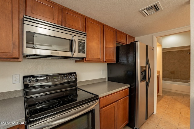 kitchen with appliances with stainless steel finishes, a textured ceiling, and light tile patterned flooring