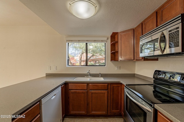 kitchen with sink, light tile patterned floors, stainless steel appliances, and a textured ceiling