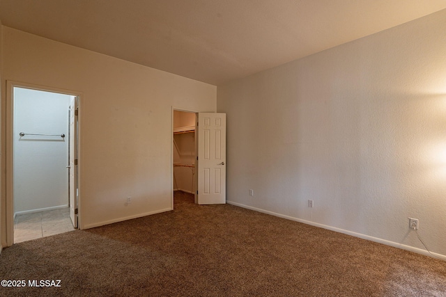 unfurnished bedroom with carpet, a walk in closet, and a closet