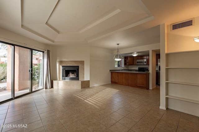 unfurnished living room featuring a raised ceiling, built in shelves, and light tile patterned flooring