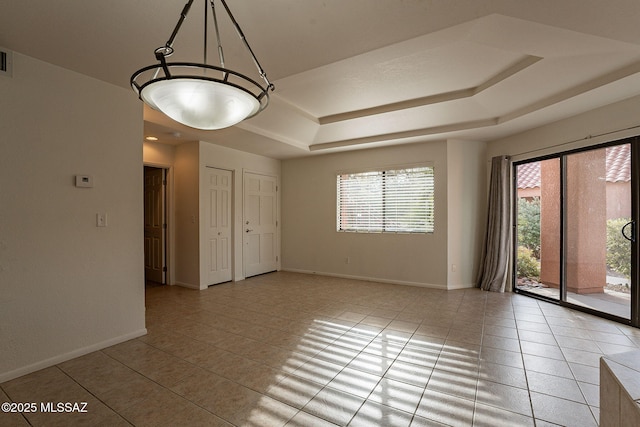 unfurnished room featuring a tray ceiling and light tile patterned flooring