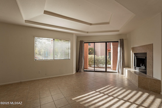 unfurnished living room with a raised ceiling, light tile patterned floors, and a fireplace