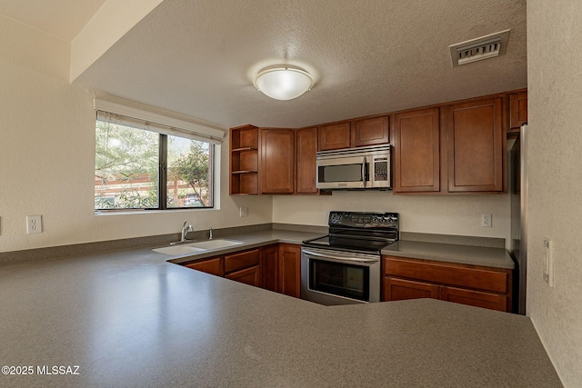 kitchen with kitchen peninsula, sink, stainless steel appliances, and a textured ceiling