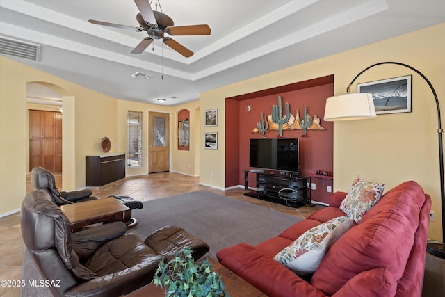 living room with light tile patterned floors, a tray ceiling, and ceiling fan