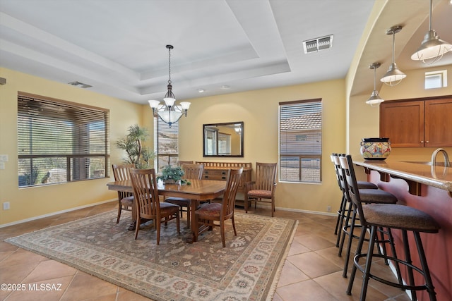 dining area featuring a raised ceiling, a notable chandelier, a healthy amount of sunlight, and light tile patterned flooring