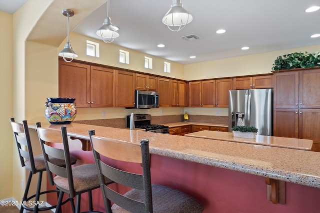 kitchen featuring hanging light fixtures, kitchen peninsula, a breakfast bar area, and appliances with stainless steel finishes