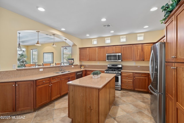 kitchen featuring kitchen peninsula, stainless steel appliances, sink, decorative light fixtures, and a kitchen island