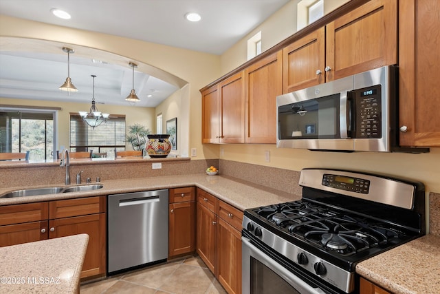 kitchen featuring light stone countertops, sink, a notable chandelier, decorative light fixtures, and appliances with stainless steel finishes