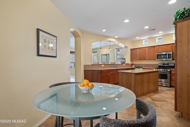 kitchen with appliances with stainless steel finishes, a center island, light tile patterned floors, and sink