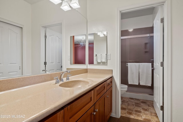 bathroom featuring ceiling fan, vanity, a shower with shower door, and toilet