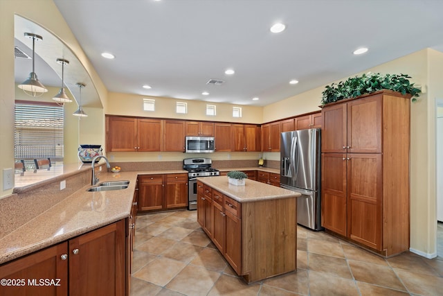 kitchen featuring pendant lighting, sink, light stone countertops, appliances with stainless steel finishes, and kitchen peninsula