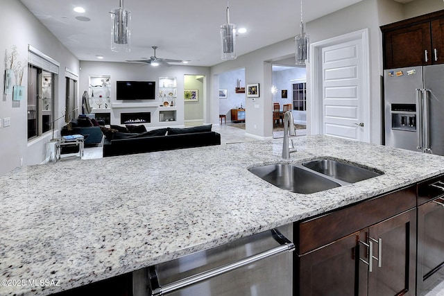 kitchen featuring hanging light fixtures, light stone countertops, sink, and appliances with stainless steel finishes