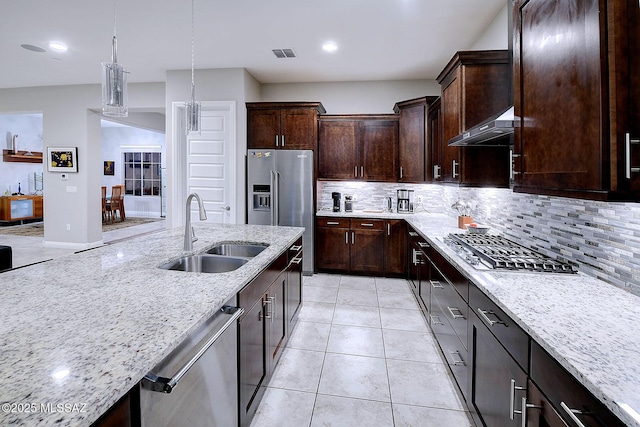 kitchen featuring sink, hanging light fixtures, exhaust hood, stainless steel appliances, and light stone countertops