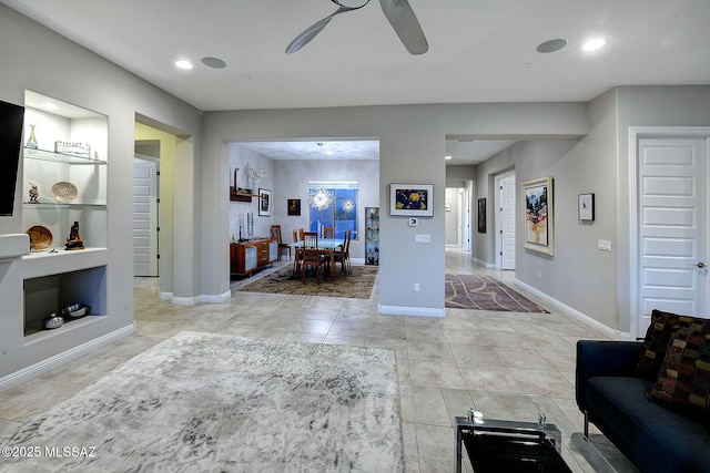 tiled living room featuring built in shelves and ceiling fan