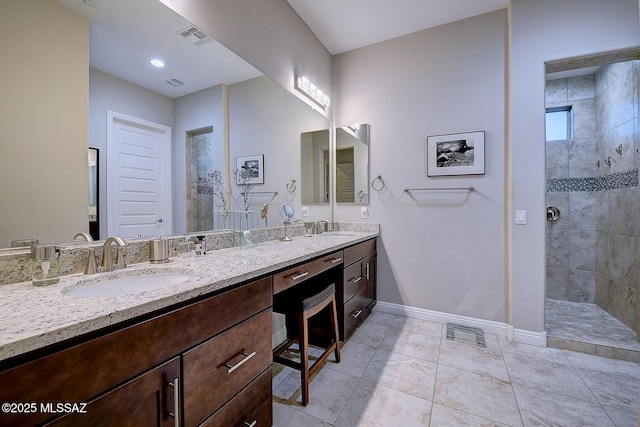 bathroom featuring vanity, tile patterned flooring, and a tile shower