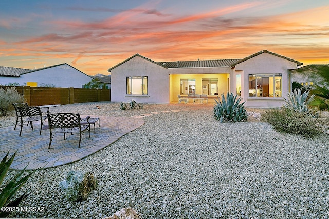 back house at dusk with a patio area