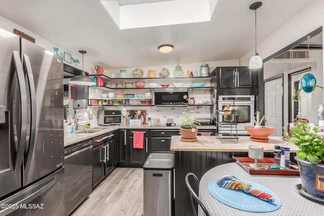 kitchen featuring decorative light fixtures, a skylight, appliances with stainless steel finishes, and sink