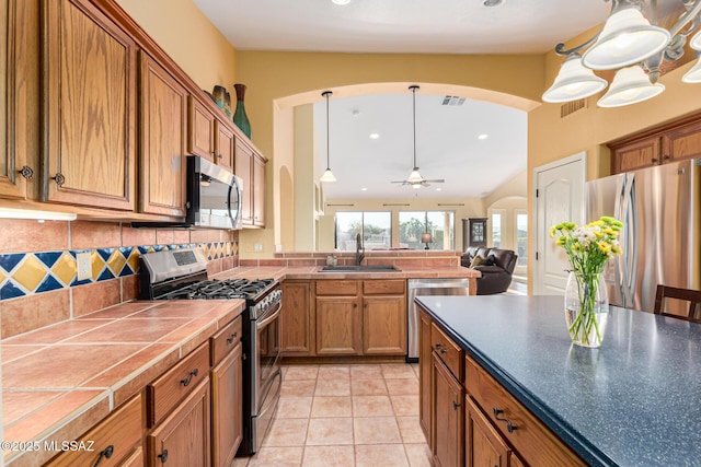 kitchen with backsplash, sink, ceiling fan, appliances with stainless steel finishes, and decorative light fixtures