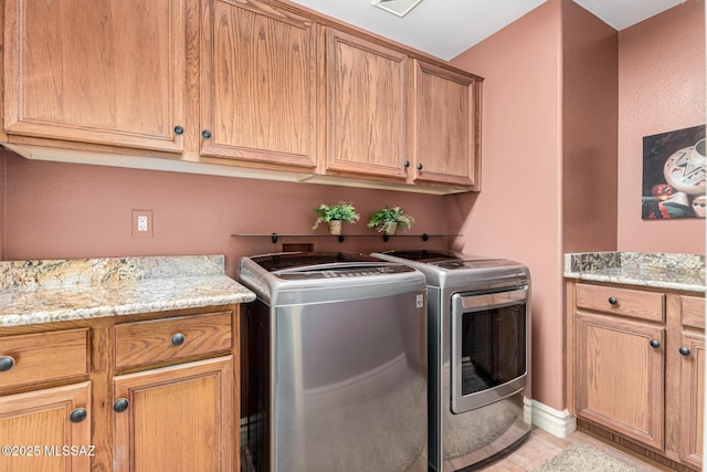 washroom with cabinets, light tile patterned floors, and washing machine and clothes dryer