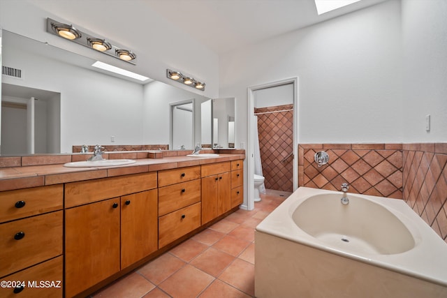 bathroom with vanity, a bath, tile patterned floors, a skylight, and toilet