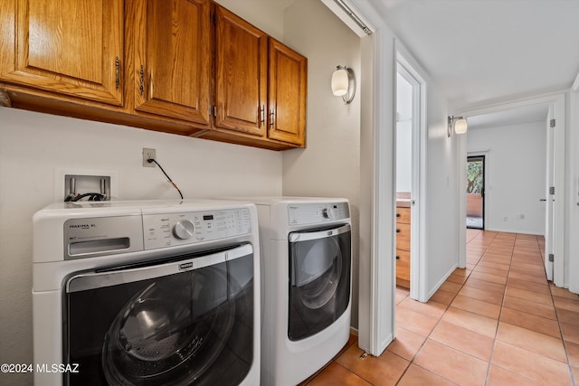 washroom featuring cabinets, light tile patterned floors, and washing machine and dryer