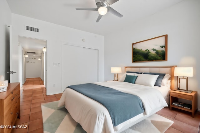 tiled bedroom with ceiling fan and a closet