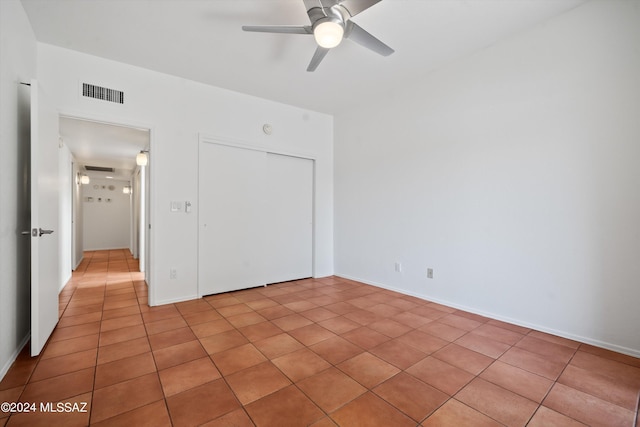 unfurnished bedroom with light tile patterned floors, a closet, and ceiling fan