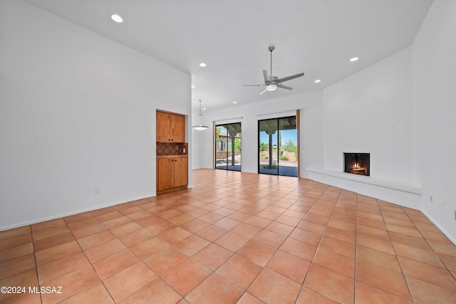 unfurnished living room featuring ceiling fan, a large fireplace, and light tile patterned floors