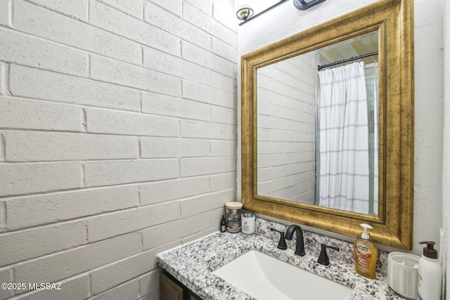 full bathroom featuring concrete block wall and vanity