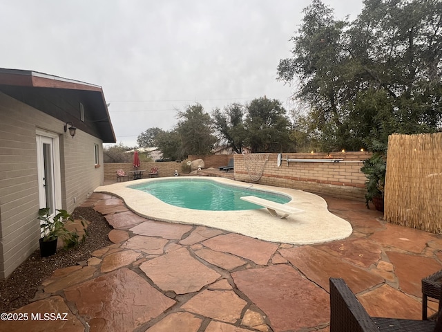 view of swimming pool with a patio area, a fenced backyard, a diving board, and a fenced in pool